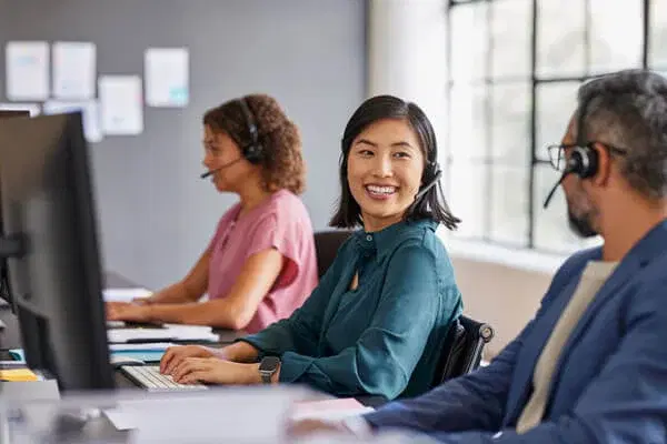 Happy call center team members working with headsets in a modern office